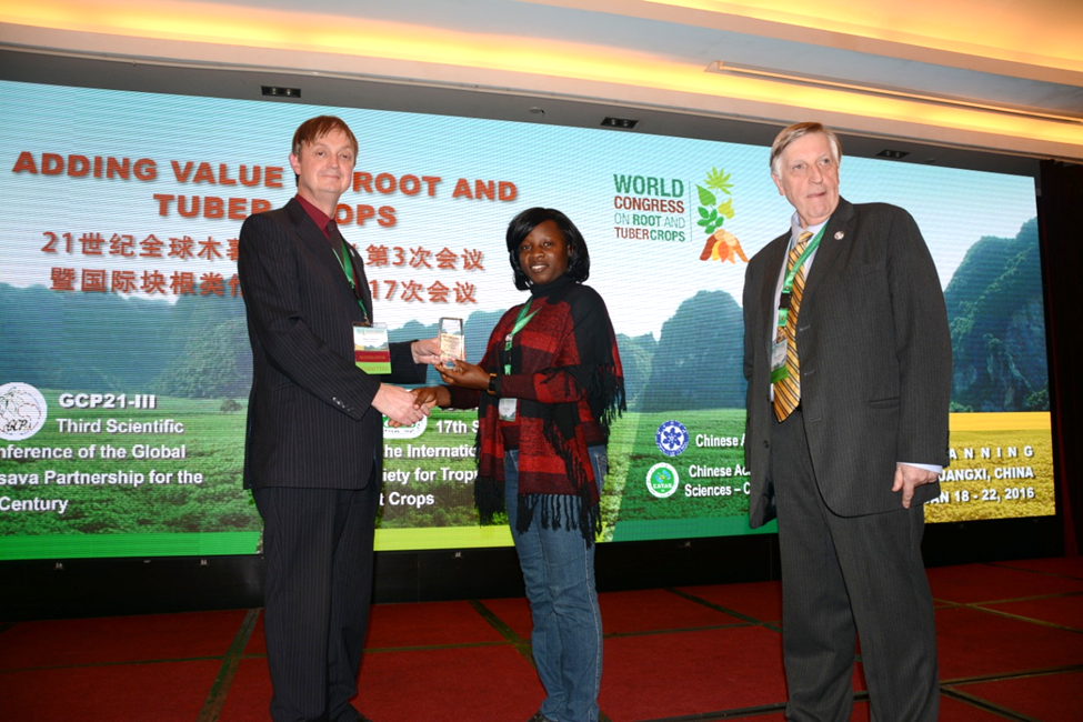 Jacinta Akol receives the ‘Pat Coursey’ award from Keith Tomlins, president of the International Society for Tropical Root Crops (ISTRC). Looking on is Claude Fauqet, co-founder of the Global Cassava Partnership for the 21 Century (GCP2) (photo: WCRTC)